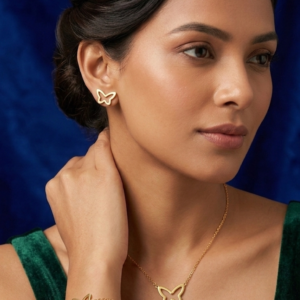 A woman with an elegant updo wearing the Azure gold lariat necklace, square blue crystal stud earrings, and matching bracelet, styled with a dark green velvet dress.