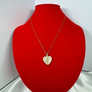 A gold pave crystal heart locket necklace resting on a rich blue velvet background, surrounded by vintage-inspired items like a gold pocket watch and an antique book, conveying a luxurious and timeless aesthetic.